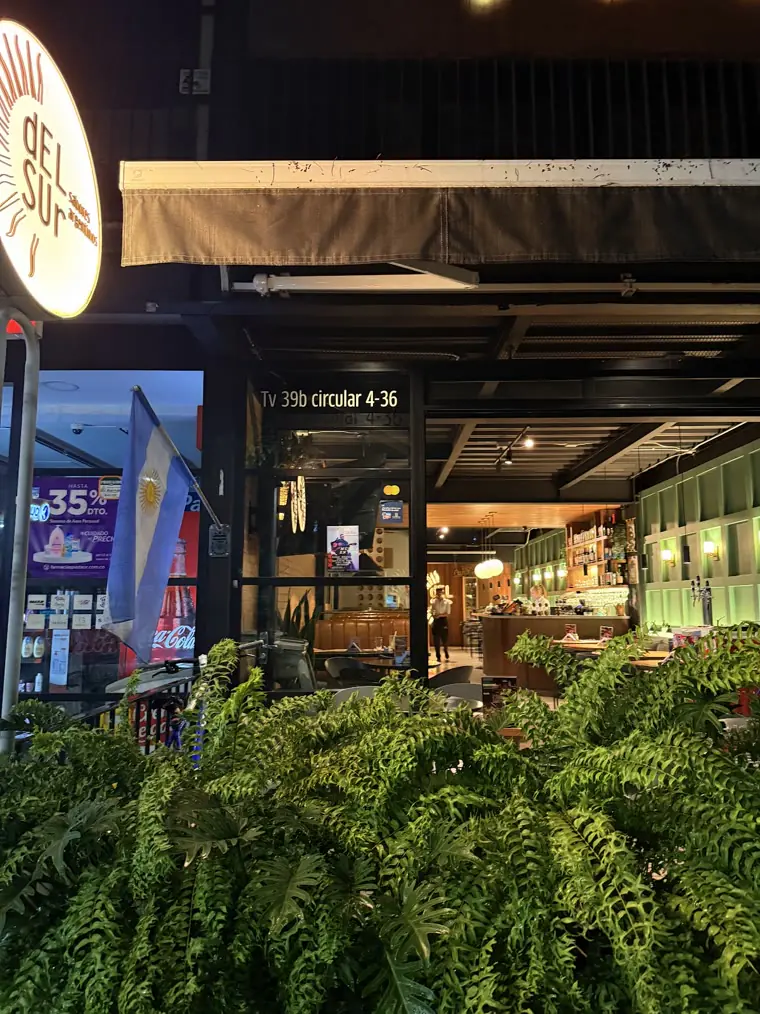 Fachada de Del Sur de noche, con plantas al frente
